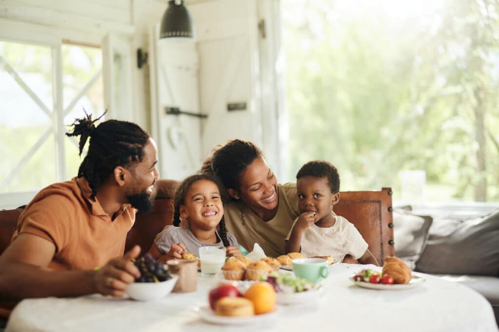 Happy black family having breakfast at dining table.